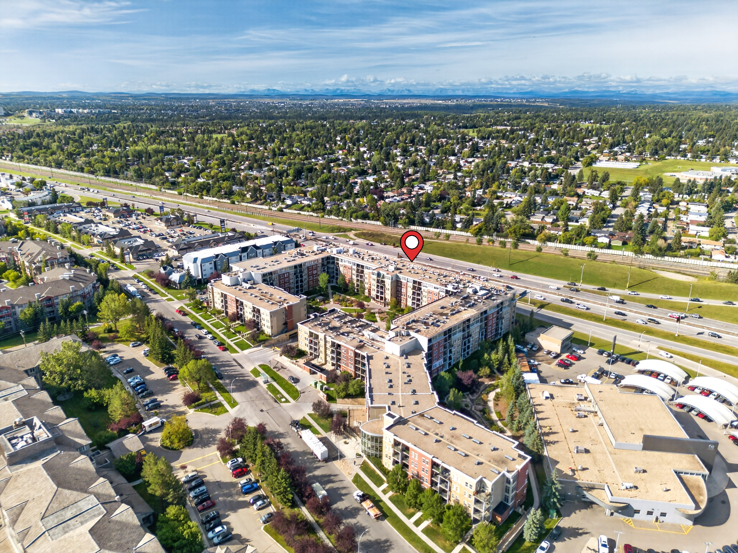 Aerial photograph of a Calgary condo development with a location pin marking nearby amenities